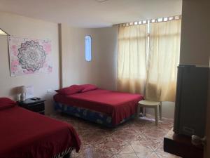 1 dormitorio con 2 camas y TV de pantalla plana en Hostal Malania, en Manta