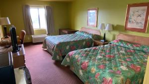 a hotel room with two beds and a flat screen tv at Sunset Inn-Rolla in Rolla