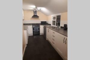 a kitchen with white cabinets and a black stove top oven at Cornish village house close to beaches & amenities in Porthscatho