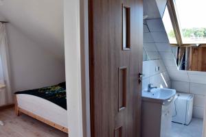 a bathroom with a sink and a bed and a door at W Ziołowym Ogrodzie - pokoje z dostępną kuchnią, apartament in Kudowa-Zdrój