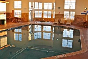 ein großer Pool in einem Gebäude mit Tischen und Stühlen in der Unterkunft Arbuckle Lodge Gillette in Gillette