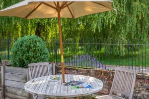 - une table en bois avec un parasol sur la terrasse dans l'établissement Huge luxury loft cottage in historic country estate - Belchamp Hall Hayloft, à Belchamp Otten