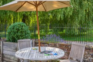 una mesa de madera con una sombrilla en el patio en Huge luxury loft cottage in historic country estate - Belchamp Hall Hayloft en Belchamp Otten