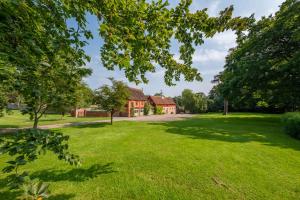 a house in the middle of a grassy yard at Stylish luxury cottage in historic country estate - Belchamp Hall Coach House in Sudbury