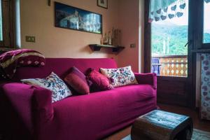 un sofá púrpura con almohadas en la sala de estar en "Lo méquio de Emilie" 2 passi da centro e piste en Valtournenche