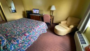 a hotel room with a bed and a chair and a desk at Sunset Inn-Rolla in Rolla