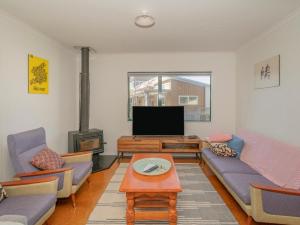 ein Wohnzimmer mit einem Sofa und einem TV in der Unterkunft Idyll Thyme - Hahei Holiday Home in Hahei