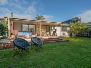 a house with two chairs in front of a yard at Idyll Thyme - Hahei Holiday Home in Hahei