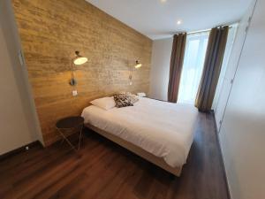 a bedroom with a white bed and a brick wall at Legend Majestic - 3 chambres - Parking privé GRATUIT - Centre Ville - Quai de Saône - Gare - fibre in Mâcon +18 photos