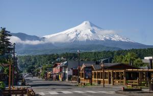 a snow covered mountain in a town with a street at Rangi Pucon in Pucón