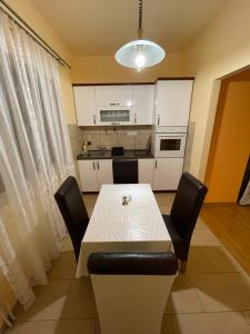 cocina con mesa blanca y sillas negras en Apartman Alibi, en Boljevac
