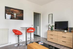 een woonkamer met twee rode krukken en een televisie bij Charming studio 15 min from Lille in Marcq-en-Baroeul - Welkeys in Marcq-en-Baroeul