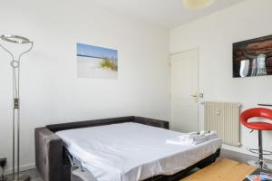 een ziekenhuisbed in een kamer met een rode stoel bij Charming studio 15 min from Lille in Marcq-en-Baroeul - Welkeys in Marcq-en-Baroeul