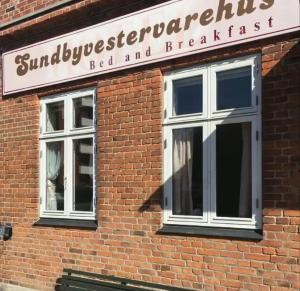 un cartel en un edificio de ladrillo con dos ventanas en Sundbyvestervarehus, en Copenhague