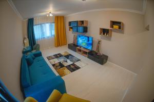 a living room with a blue couch and a tv at La Stejari Apartment in Suceava