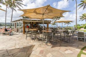 Un restaurante con mesas y sillas y una sombrilla. en Three Tables Retreat, en Haleiwa