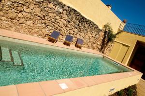 a swimming pool with chairs next to a building at Ca l'Helena in Castellet +20 photos