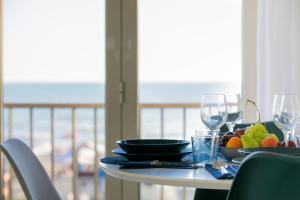 a table with a plate of fruit and wine glasses at Nuovo Appartamento sulla spiaggia con larga terrazza di 70 mq e posto auto privato in Anzio