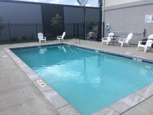 Una gran piscina azul con sillas y una mesa. en Quality Inn & Suites Blue Springs - Kansas City, en Blue Springs