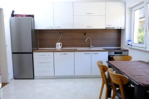 a kitchen with white cabinets and a table and a refrigerator at Urban Apartment Visoko in Visoko