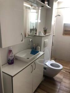 a white bathroom with a toilet and a sink at Apartment in the center of the old city, Budžak 14 in Sarajevo
