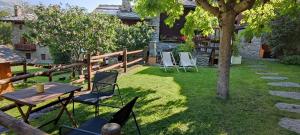 un jardín con sillas, una mesa y un árbol en La Casetta di Lele e Schina, en Arvier