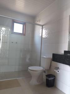 a bathroom with a toilet and a shower and a window at Chalés Recanto Vista do Valle in Monte Verde
