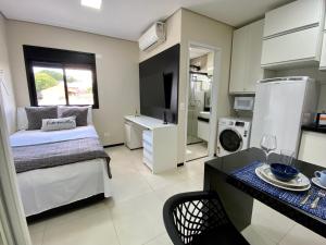 a bedroom with a bed and a kitchen with a table at Studio32B decorado Bairro Fragata in Marília