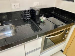 a kitchen with a black counter top with a sink at Studio32B decorado Bairro Fragata in Marília