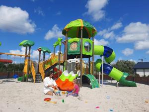 a woman and a child playing in the sand at a playground at Goose Home and Garden in Łeba