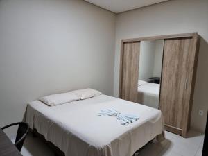 1 dormitorio con cama blanca y espejo en Flat Genoveva en Tangara da Serra