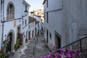 eine Gasse mit weißen Gebäuden und lila Blumen in der Unterkunft Casa da Judiaria in Castelo de Vide