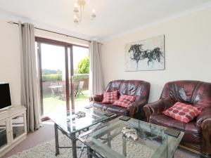 a living room with leather couches and a glass table at Ryecross Farm Cottage in Melbury Abbas