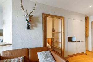 salon z kanapą i głową jelenia na ścianie w obiekcie Cosy flat with terrace in Huez - Welkeys w mieście LʼHuez