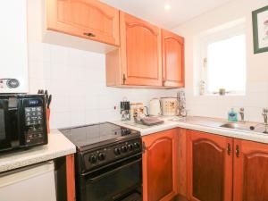 una cucina con armadi in legno e forno a piano cottura nero di Ryecross Farm Cottage a Melbury Abbas