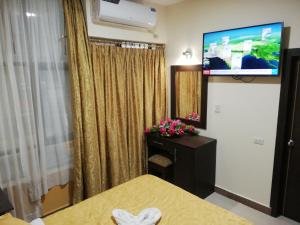 a room with a bed and a flat screen tv at Victoria Suites Hotel in Santo Domingo de los Colorados