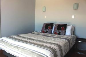 ein Schlafzimmer mit einem Bett mit Kissen darauf in der Unterkunft Poppy Apartment in Coromandel Town