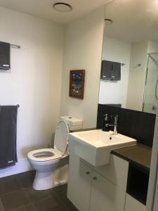 a bathroom with a white toilet and a sink at The Perfect Host @ Curtis Apartments in Gladstone