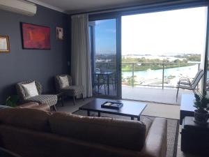 sala de estar con sofá, mesa y balcón en The Perfect Host @ Curtis Apartments, en Gladstone