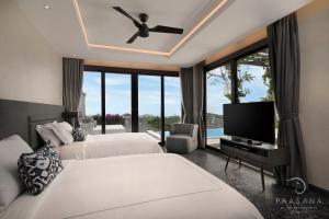 a bedroom with two beds and a flat screen tv at Prasana by Arjani Resorts in Uluwatu