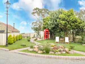 un jardín con una cabina de teléfono rojo en un patio en The Hayshed, en Whitby