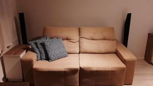 a brown couch with two pillows on top of it at Apto Cruzeiro do Sul com Wi-Fi in São José dos Pinhais