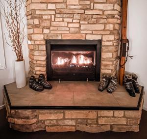 a fireplace with several pairs of shoes in front of it at Ajax Ski Club in Mount Buller