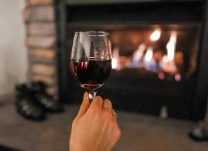 a person holding a glass of wine in front of a fireplace at Ajax Ski Club in Mount Buller +25 photos