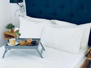 a tray of food on a bed with white pillows at Mica Apartments in Sere Kunda