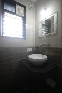 een badkamer met een witte wastafel en een raam bij RNB Beach Stay in Anjuna