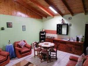 sala de estar con mesa, sillas y TV en Cassidini House, en Monteverde