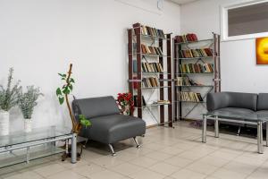 a room with two chairs and a book shelf with books at Pansionat Energetik in Nilovka