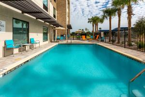 een zwembad met blauwe stoelen en een gebouw bij Holiday Inn Express & Suites - Ft Myers Beach-Sanibel Gateway, an IHG Hotel in Fort Myers Beach