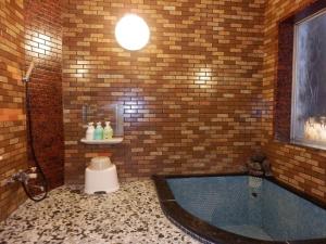 a bathroom with a bath tub in a brick wall at Murataya in Kanazawa